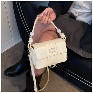 Detailed shot of beige woven leather bag with silver metal logo and beaded handle