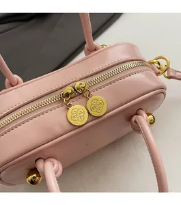 Close-up of golden dual zippers with RICA branding on pink leather Boston bag