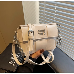 Détail du sac carré tissé crème avec logo argenté, chaîne et breloque chien ballon