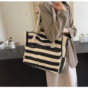 Detail of black and white striped woven tote bag with rope handle and tassel charm