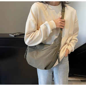 Detail of army green nylon crossbody crescent bag with woven rope zipper pull