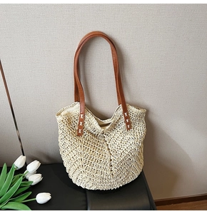 Detail view of beige straw tote bag featuring V-shaped woven pattern and brown leather straps