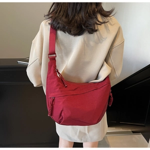 Detail of red nylon dumpling crossbody bag with adjustable strap and braided zipper pull