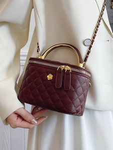 Quilted burgundy crossbody box bag with golden metal handle and camellia floral detail