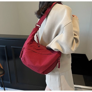 Detailed view of the red nylon messenger bag showing soft texture and woven zipper pull