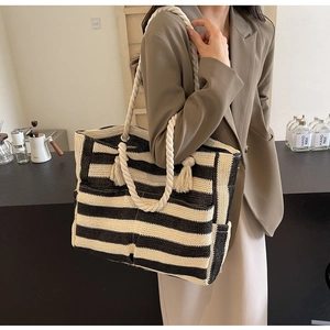 Close-up of woven stripe tote bag with cotton rope handles and tassel details on the side