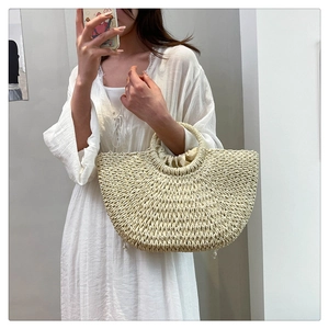 Detail of hand-woven off-white half-moon beach bag with round handle and drawstring liner
