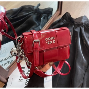 Détail du sac bandoulière en cuir verni rouge tressé avec chaîne argentée et logo