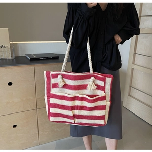 Detail of red and white striped woven tote bag with cotton rope handles and fringe tassels
