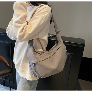 Detailed side view of grey nylon crescent bag with adjustable strap on a model