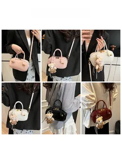 Detail view of colorful Boston bags in pink, white, black, and red with teddy bear charm