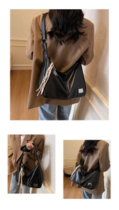 Close-up of black leather hobo bag with silver logo plate and colorful braided pendant