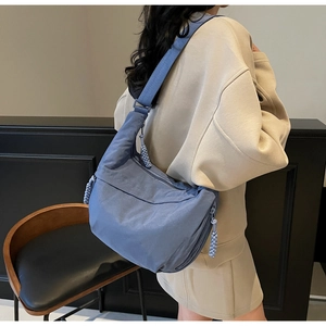 Morandi blue nylon dumpling bag worn by model showing side view and soft texture
