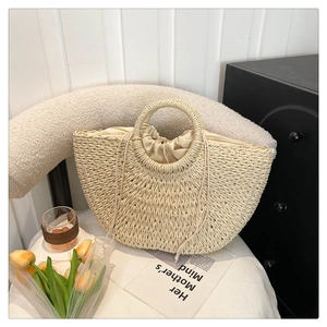 Detailed shot of the woven straw bag with beige drawstring lining and ring handles