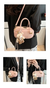 Pink Boston bag with detachable strap and cute bear charm shown on model in detailed view