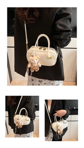 Detail of cream Boston bag with gold hardware, dual handles and a small plush bear charm