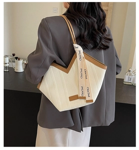 Detail of white embossed leather tote bag with V-cut opening and brown trim accents