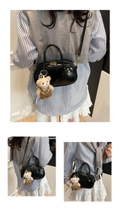 Detail of black glossy Boston bag with a cute bear charm and adjustable shoulder strap