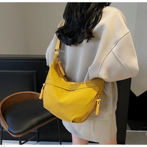 Close-up of bright yellow nylon crescent bag featuring a woven knot zipper detail