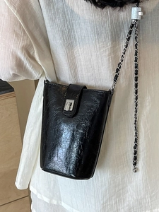 Minimalist black glossy leather bucket bag with silver chain strap and metal lock