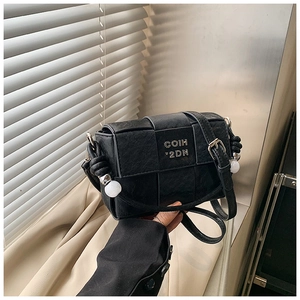 Detail of woven black square bag with metal logo and unique beaded knot handle