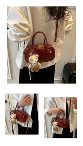 Detail of reddish brown Boston bag with smooth leather finish and a cute bear charm