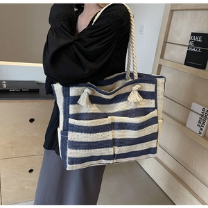 Detail of blue and white striped woven tote bag with cotton rope handles and fringe decoration