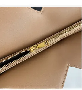 Detailed close-up of smooth gold metal zipper and lychee grain leather texture on tote bag