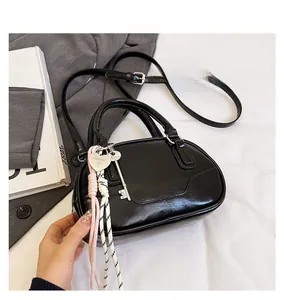 Detail view of black leather bowling bag with silver heart charm and adjustable strap