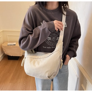 Close-up of the beige nylon dumpling bag showing detailed fabric texture and woven strap