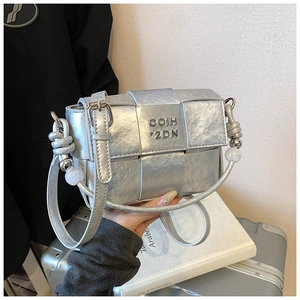 Silver metallic woven crossbody bag featuring a knotted strap and large pearl beads