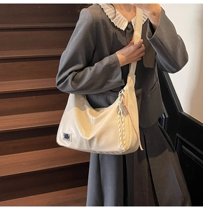 Close-up of white leather hobo bag featuring a metal logo detail and rope zipper charm