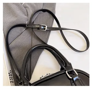 Detail of glossy black patent leather bowling bag with silver metal buckles and slim strap