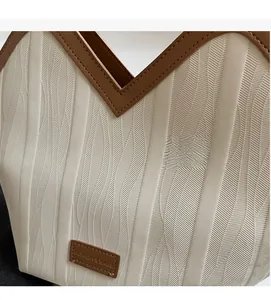 Detail of herringbone pattern cream tote bag with brown leather trim and fashion tag