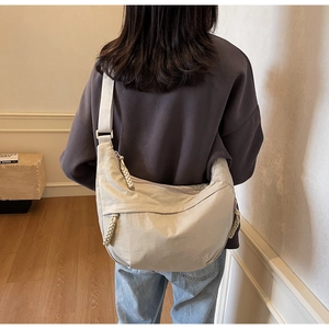 Detail view of large cream dumpling bag with knot zipper on model back indoors