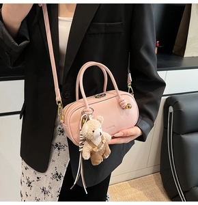 Pink leather Boston bag with teddy bear charm shown against a stylish blazer outfit