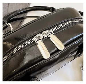 Detail of premium black leather bag featuring smooth dual silver metal zippers