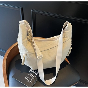 Detail of minimalist cream crescent crossbody bag featuring woven knot accents and zipper