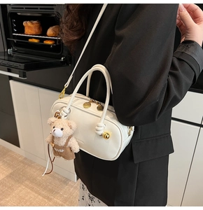 Detail of white Boston bag with gold hardware and a cute teddy bear plush charm