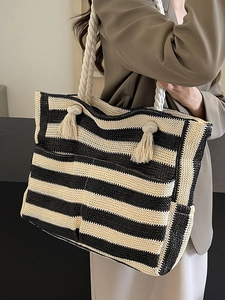 Woven striped tote bag with rope handles and tassel details for summer beach travel