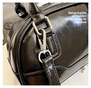 Detail of silver metal hook and detachable strap on black shiny leather bowling bag