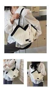 Detail of a large white pleated tote bag with black leather trim and woven decorative strap