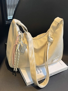 Creamy white leather hobo bag with unique tennis racket charms and wide shoulder strap