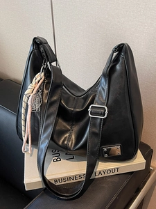 Vintage large black hobo shoulder bag with tennis racket pendant on business book