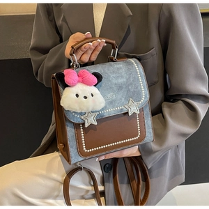 Detail of blue denim and brown leather bag with pearl rivets and silver star charms