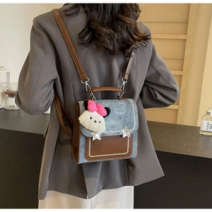 Detail view of denim patchwork backpack with star hardware and plush charm on the back