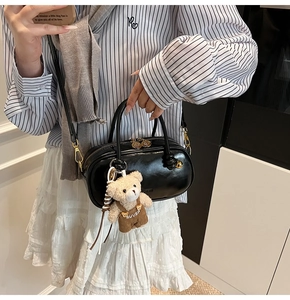 Close-up of black leather Boston bag with teddy bear charm and gold hardware detail