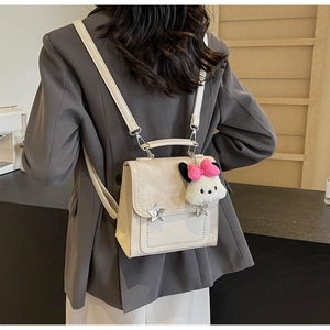 Detail of cream mini backpack with silver star studs and cute plush puppy charm