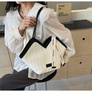 Detail of the white pleated tote bag featuring black leather trim and contrast straps
