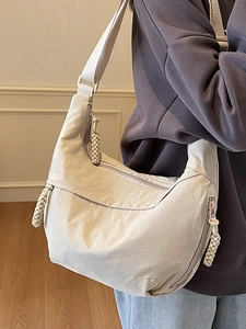 Minimalist large ivory nylon hobo bag featuring multiple zip pockets and woven rope pullers